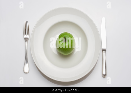 Dieta - verde mela su una piastra bianca con coltello e forchetta Foto Stock