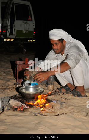 Bedouin uomini pasto di cottura nel deserto sul fuoco di notte sul deserto trek escursione, Sinai, Egitto Foto Stock