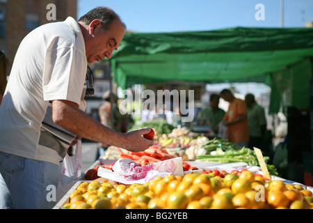 Uomo che sceglie i pomodori in una bancarella di mercato nel sud della Spagna Foto Stock