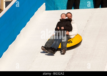 Regno Unito, Inghilterra, Manchester Piccadilly, giardini, padre e figlia godendo di corsa sulla neve artificiale slitta Foto Stock