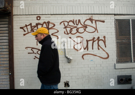 Un uomo cammina passato una coperta di graffiti parete nel Greenwich Village quartiere di New York Foto Stock