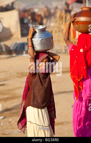 Ragazza che trasportano l'acqua sul suo capo al Camel Fair in Pushkar India Foto Stock