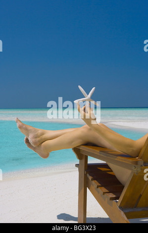 Donna che mantiene seastar sulla spiaggia, Maldive, Oceano Indiano, Asia Foto Stock