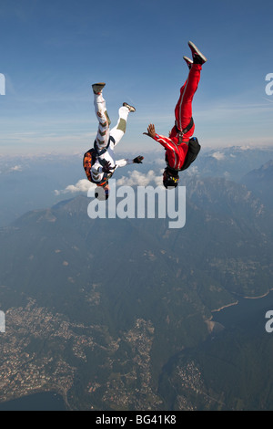 Skydivers sono battenti a testa in giù e provare a trattenere ciascun altro. In questa posizione di freefly il team potrà ottenere una velocità elevata in caduta libera. Foto Stock