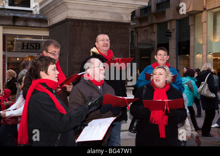 Regno Unito, Inghilterra, Manchester, St Annes Square membri del coro canti di natale per raccogliere fondi per beneficenza Foto Stock