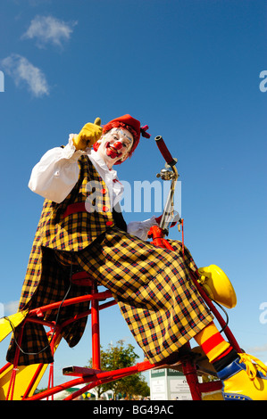 Clown su triciclo contro il cielo blu Foto Stock