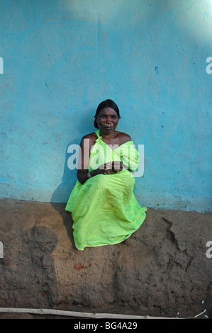 Donna seduta nel tardo pomeriggio di sole blu contro il muro di casa in Mali villaggio tribale, Jeypore district, Orissa, India, Asia Foto Stock