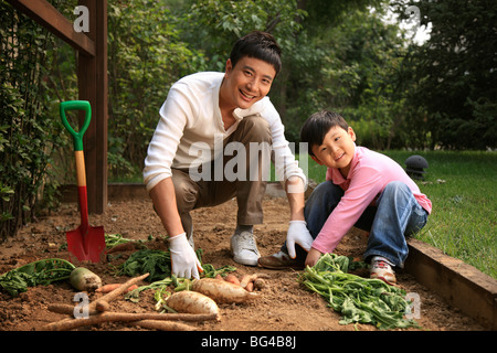 Ragazzo lo scavo di verdure con suo padre Foto Stock