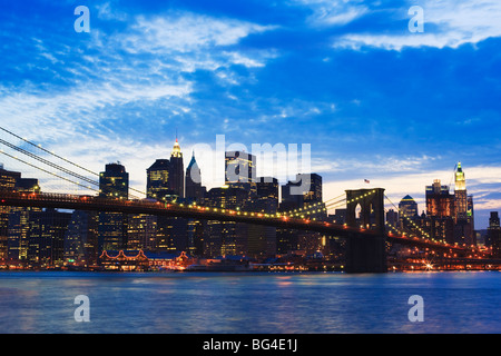 Ponte di Brooklyn Bridge spanning dell'East River e la parte inferiore di Manhattan skyline al tramonto, New York New York, Stati Uniti d'America Foto Stock