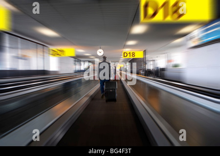 Imprenditore con bagagli sul tapis roulants all'aeroporto Schiphol di Amsterdam, Paesi Bassi, Europa Foto Stock