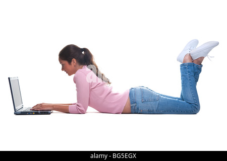 Giovane donna in abbigliamento casual giacente su un pavimento bianco utilizzando un computer portatile, schermata vuota per il vostro messaggio. Foto Stock