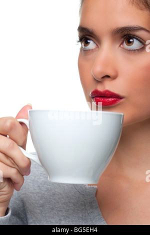 Donna che mantiene un tazza bianca circa per bere un tè come lei sta pensando a qualcosa, sfondo bianco. Foto Stock