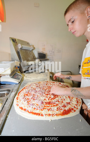 Israele, Tel Aviv, pizzeria la preparazione della pizza uomo si sparge scaglie di formaggio sulla base Foto Stock