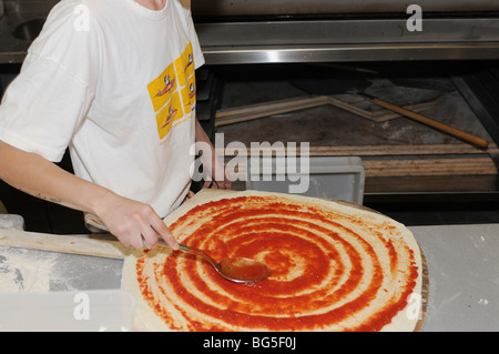 Israele, Tel Aviv, pizzeria la preparazione della pizza uomo si diffonde la salsa di pomodoro sulla base Foto Stock