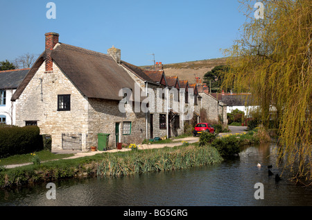 Tradizionale, inglesi, pittoresco villaggio in Dorset, Inghilterra con laghetto, anatre e edifici d'epoca in una giornata di sole. Foto Stock