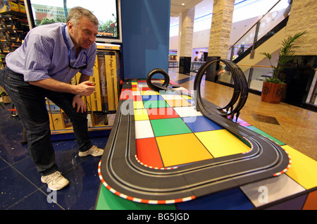 Un uomo che gioca con un motorino giocattolo racetrack, Dubai, Emirati Arabi Uniti Foto Stock