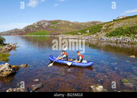 Due fratelli che indichi in una doppia canoa gonfiabile sul Loch un Chadh-fi dal Skerricha, Highland, Scozia Foto Stock