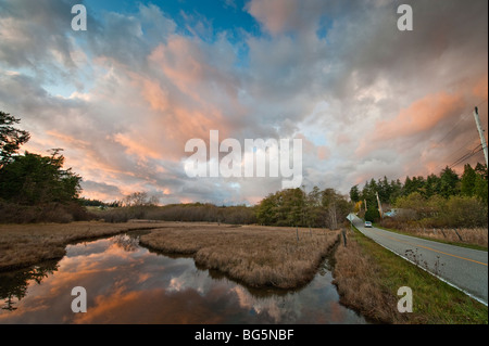 Si illumina al tramonto le nuvole sopra il Lummi Island, Washington slough e viene riflessa nell'acqua facendo un bellissimo effetto. Foto Stock