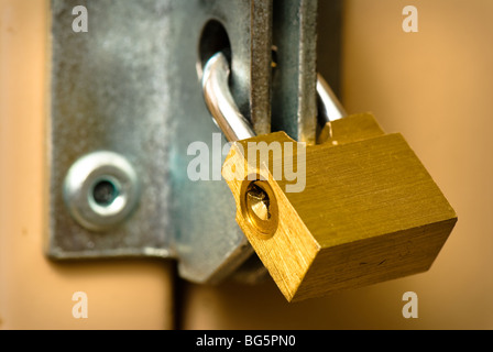 Tradizionale a forma di lucchetto in ottone con la tecnica keyhole attaccato a un armadietto. Foto Stock