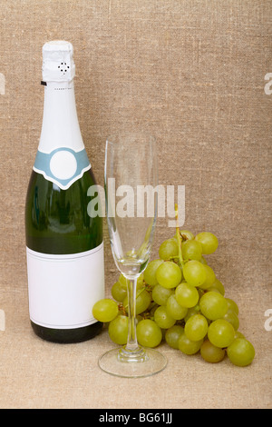 Still-life da una bottiglia di vino spumante, un bicchiere e uva cluster Foto Stock