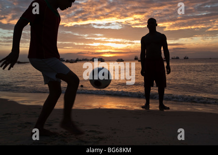 I giovani di giocare a calcio al tramonto lungo le coste dell'Oceano Indiano a Zanzibar, Tanzania. Foto Stock