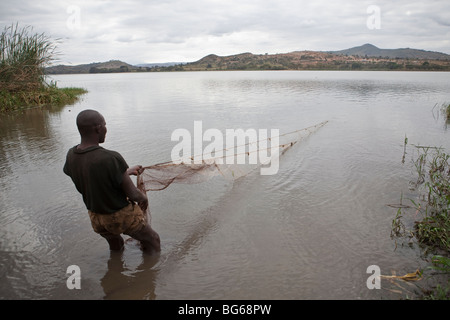 Un pescatore tira in una rete lungo le rive del lago Babati nel centro della Tanzania. Foto Stock