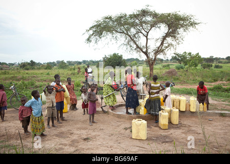 I bambini di pompare acqua da una zona rurale bene nella città di Amuria nell est dell Uganda. Foto Stock