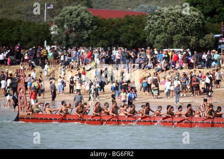 Un Waka Taua (canoe da guerra) passa spettatori su Te Ti Bay durante il Waitangi Day celebrazioni, Nuova Zelanda Foto Stock