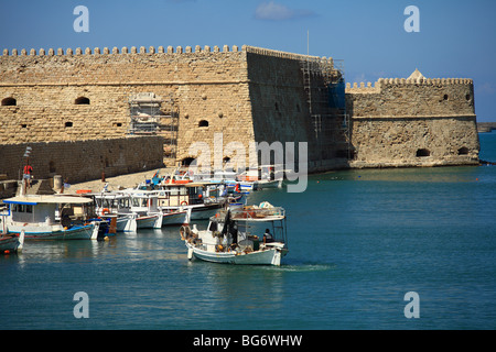Un caicco set off da Heraklion porto di pesca per una serata di pesca, con l'epoca veneziana Koule fortezza dietro Foto Stock