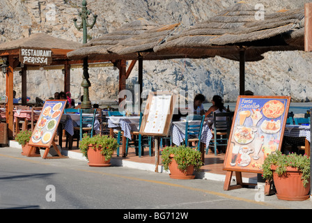 Ci sono molti ristoranti, taverne e bar presso la spiaggia strada lungo il nero costa sabbiosa di Perissa. Perissa, Santori Foto Stock
