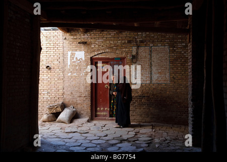 Due womenatg l'entrata di una casa tradizionale nel centro storico della città di Kashgar, provincia dello Xinjiang, Cina Foto Stock