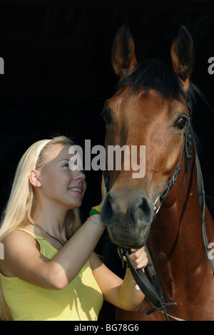 Una ragazza adolescente stallieri il suo cavallo nella stalla, Tambov, Russia Foto Stock