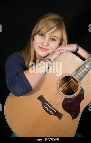 Una bella bionda ragazza adolescente con un grande carnagione e un piccolo piercing per il naso di suonare una chitarra Foto Stock