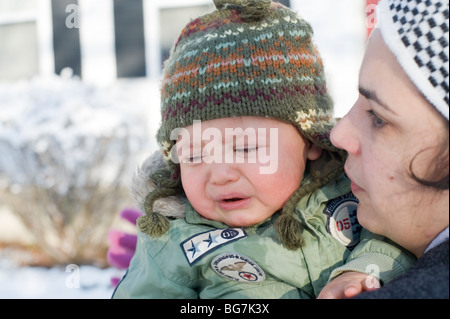 11 mese vecchio ragazzo ispanico riproduce in fresca neve caduti nel suo cortile anteriore con sua madre. Immagine modello è rilasciato. Foto Stock