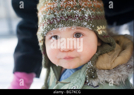 11 mese vecchio ragazzo ispanico riproduce in fresca neve caduti nel suo cortile anteriore con sua madre. Immagine modello è rilasciato. Foto Stock