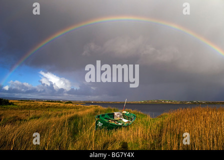 Pesca in legno barca tirata fino in canne da Oceano Atlantico come una tempesta si muove nel produrre un arcobaleno Foto Stock