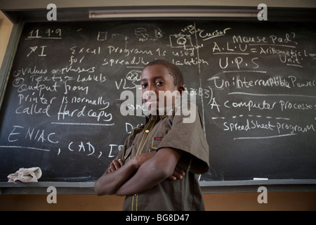 Un ragazzo si erge con fiducia di fronte a una lavagna nella classe di computer in una scuola di Moshi, Tanzania. Foto Stock