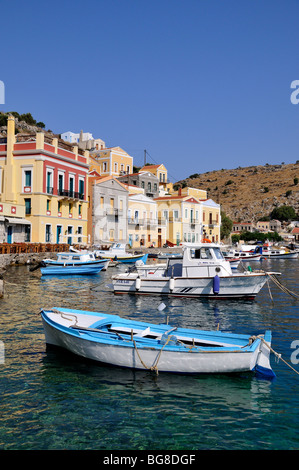 Barche da pesca nella parte anteriore di colorate case tradizionali a Symi porta, Symi Island, Grecia Foto Stock