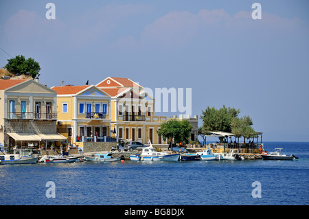 Barche da pesca nella parte anteriore di colorate case tradizionali a Symi porta, Symi Island, Grecia Foto Stock