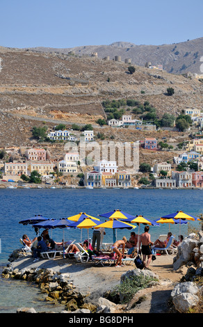 "NOS' spiaggia a Symi town e le tradizionali case colorate, Symi Island, Grecia Foto Stock