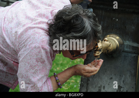 Signora da bere acqua in ottone a forma di fontana come un anatra la testa milano italia Foto Stock