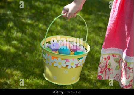 Ragazza con uovo di Pasqua nel carrello mentre si cammina sul prato Foto Stock