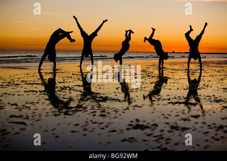 I giovani adulti salto alto durante una passeggiata sulla spiaggia. Foto Stock