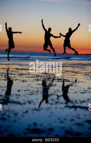 I giovani adulti salto alto durante una passeggiata sulla spiaggia. Foto Stock