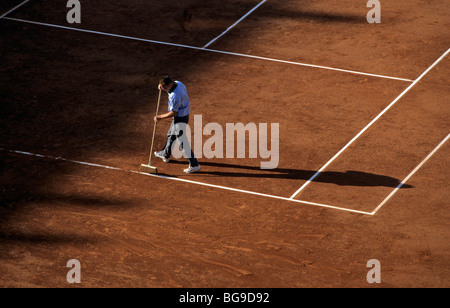 Pulizia Groundskeeper le linee di servizio su una corte di argilla Foto Stock