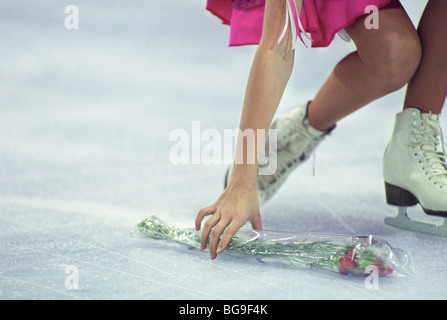 Femmina Skater ghiaccio raccogliendo dei fiori dopo le prestazioni Foto Stock