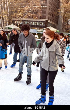 Un trio di bright joshing felice teens, 2 ragazze e un ragazzo, godere di pattinaggio sul ghiaccio al Bryant Park stagno in Manhattan New York City Foto Stock