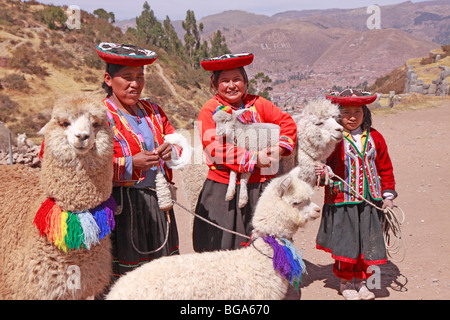 Alle donne indigene e la ragazza con alpaca presso le rovine Inca di Sacsayhuaman, Cuzco, Andes, Perù, Sud America Foto Stock