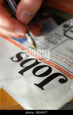 Una persona giovane reti a strascico per la carta locale in cerca di un lavoro nella sezione classificati. Foto da Jim Holden. Foto Stock