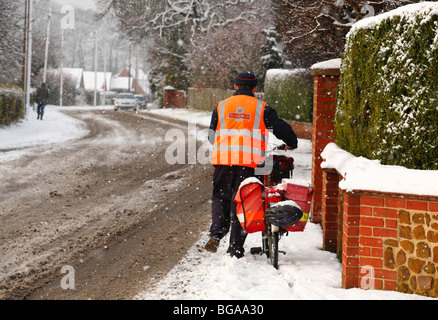 Un postino lotte attraverso la neve con la sua bicicletta per consegnare la posta natalizia. Foto Stock